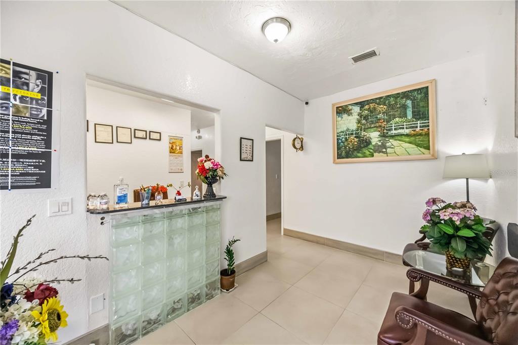 A waiting room features a glass block reception desk, tile flooring, and a framed landscape painting — 2081 TAMIAMI TRAIL, PORT CHARLOTTE, FL