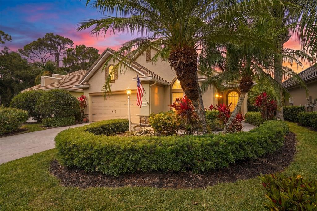 A single-story house with a beige stucco exterior, a two-car garage, and landscaped front yard — 7822 TROON COURT, LAKEWOOD RANCH, FL