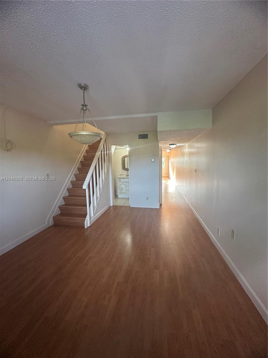 This room features wood-look flooring, a staircase with white railings, and a small bathroom — 9500 SW 3rd St # 254, Boca Raton FL 33428, BOCA RATON, FL