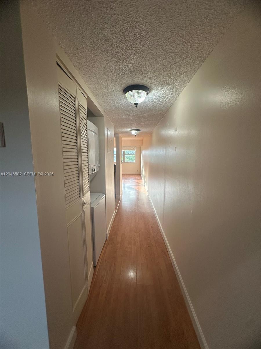 A narrow hallway with wood-look flooring leads toward a windowed room — 9500 SW 3rd St # 254, Boca Raton FL 33428, BOCA RATON, FL