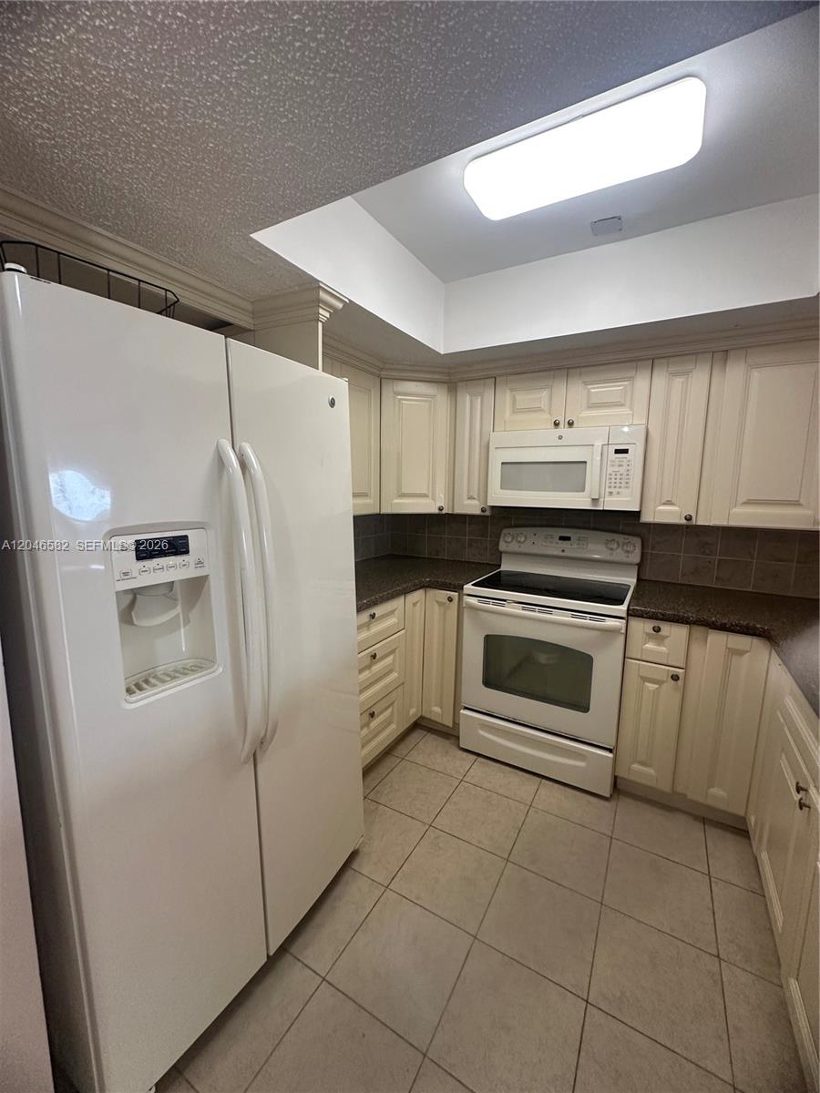 A kitchen features white cabinets, a white refrigerator, a white stove, and tiled flooring — 9500 SW 3rd St # 254, Boca Raton FL 33428, BOCA RATON, FL