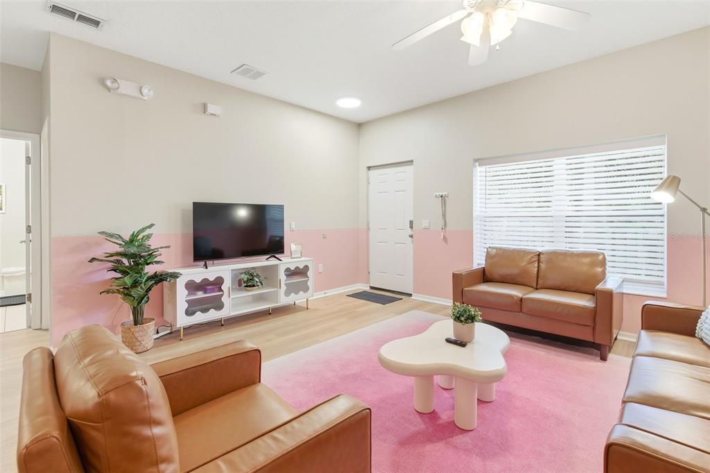 A living room features light wood flooring, a pink accent wall, and brown leather furniture — 3119 SUN LAKE COURT UNIT B, KISSIMMEE, FL