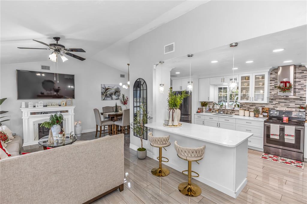 An open-concept kitchen and living area featuring white cabinetry, a breakfast bar, and a fireplace — 1390 SAN CARLOS AVENUE, DELTONA, FL