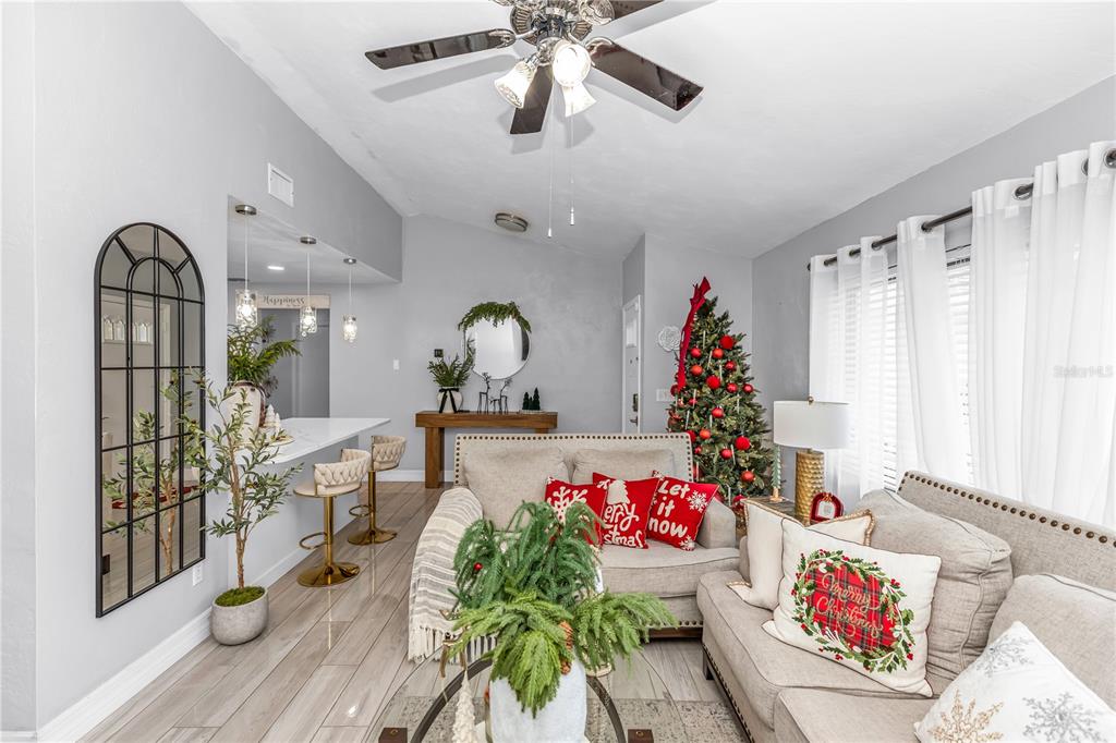 A living room with a Christmas tree, neutral sofa, breakfast bar, and arched wall mirror — 1390 SAN CARLOS AVENUE, DELTONA, FL