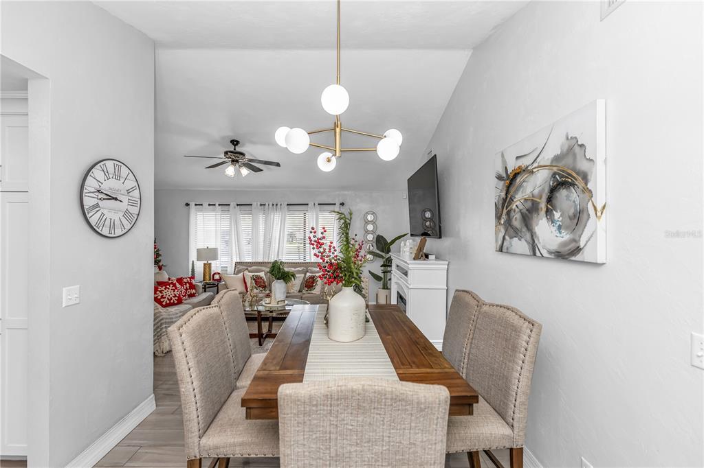 A dining area with a wooden table and chairs sits in front of a living room — 1390 SAN CARLOS AVENUE, DELTONA, FL