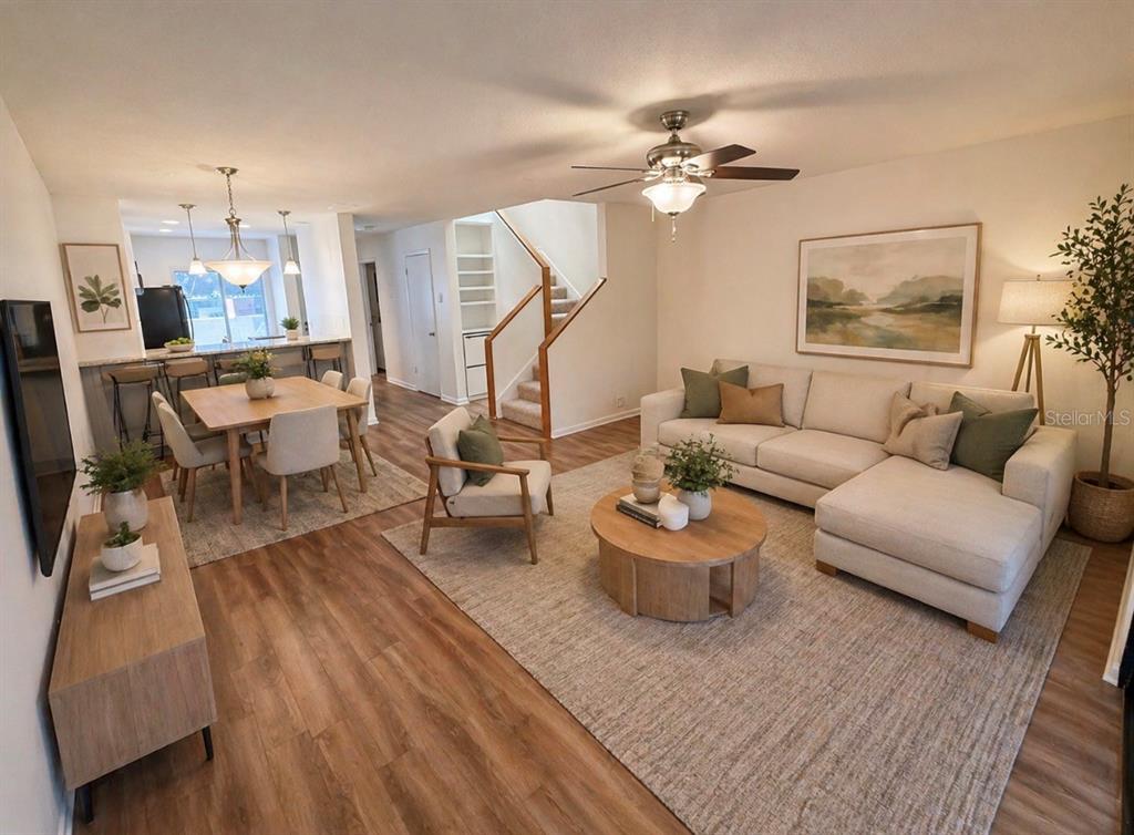 An open-concept living and dining area features wood flooring, a sectional sofa, and a staircase — 819 OAK PARK PLACE, BRANDON, FL