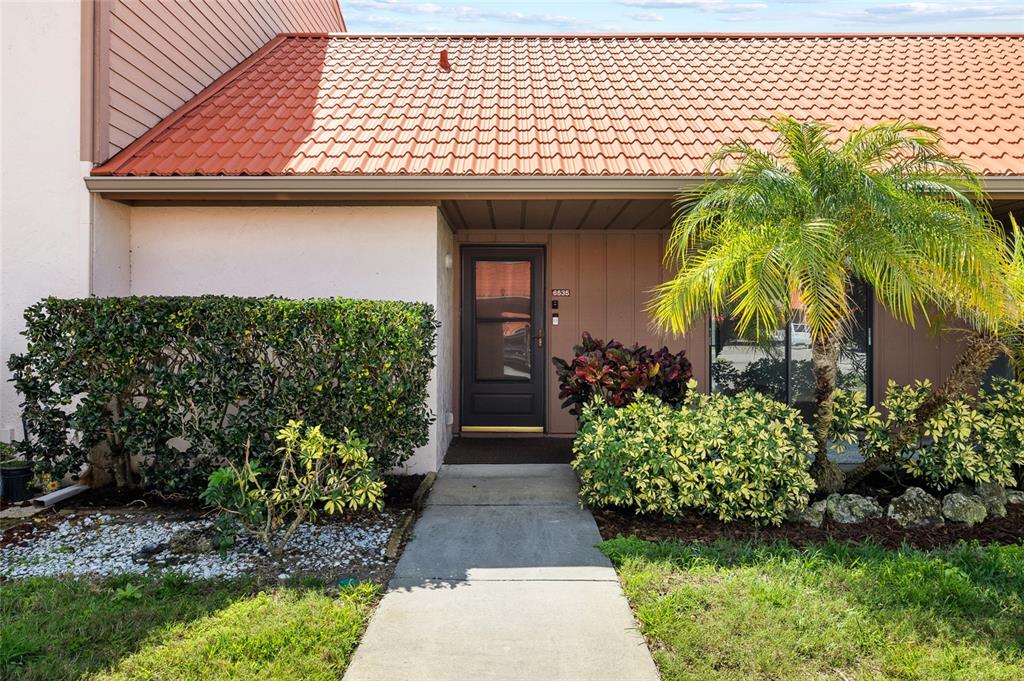 A concrete walkway leads to the front door of a home with a tiled roof — 6535 DRAW LANE UNIT 85, SARASOTA, FL