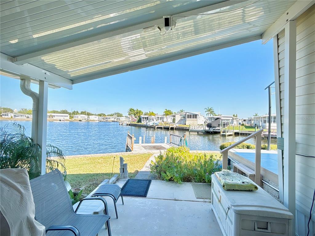 A covered patio overlooks a canal with a private dock and neighboring waterfront homes — 144 AMERICANA COURT NE UNIT 218, ST PETERSBURG, FL