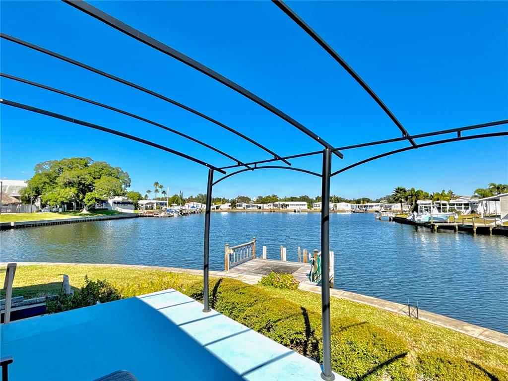 A view of a canal from a patio featuring a black metal pergola and dock — 144 AMERICANA COURT NE UNIT 218, ST PETERSBURG, FL