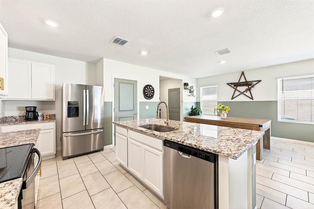 A kitchen features white cabinets, granite countertops, stainless steel appliances, and a central island — 182 AMBERWOOD WAY, UMATILLA, FL
