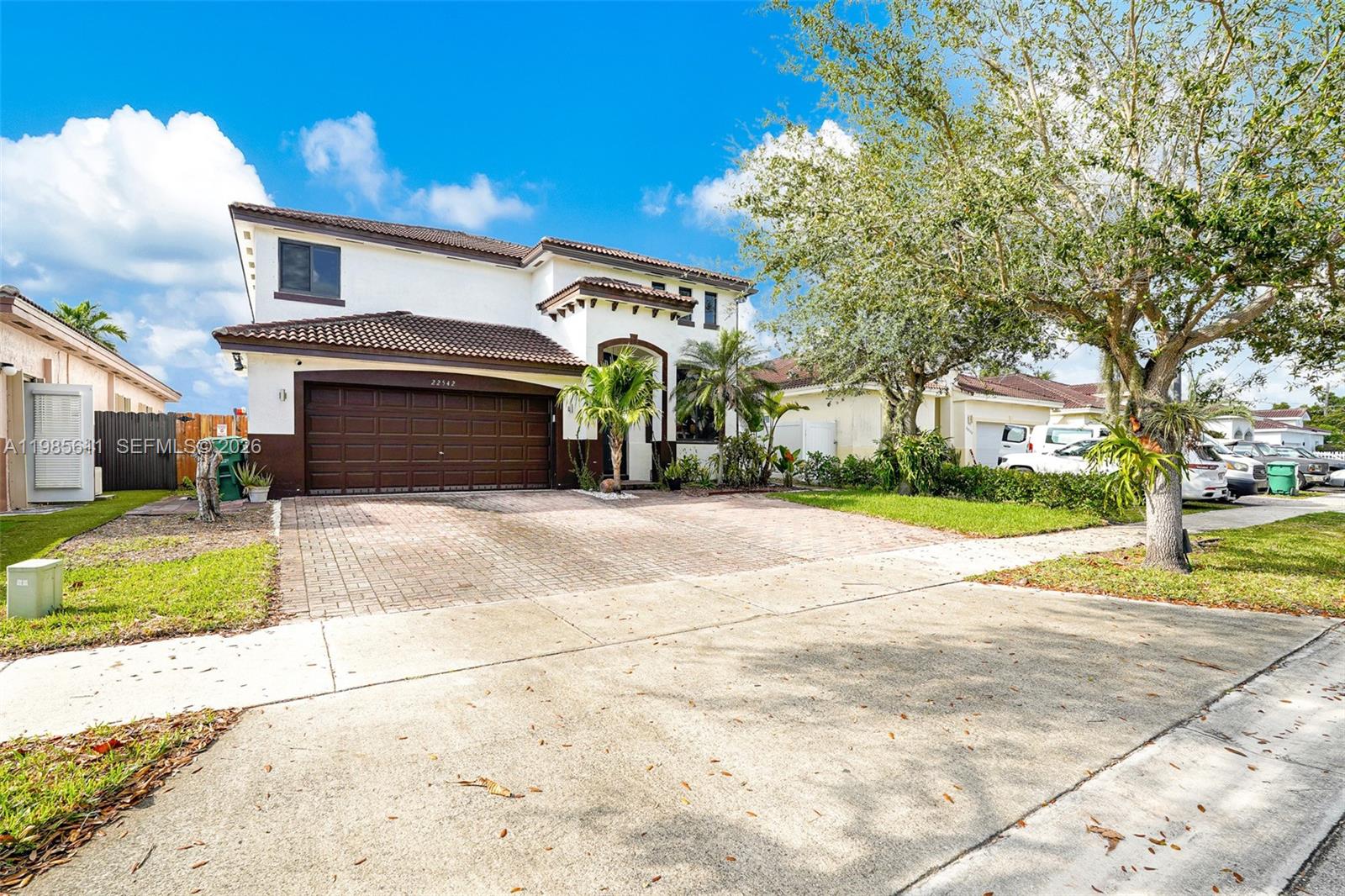 A two-story house with a brown garage door and a paved driveway under a blue sky — 22542 SW 103rd Ct, Cutler Bay FL 33190, CUTLER BAY, FL