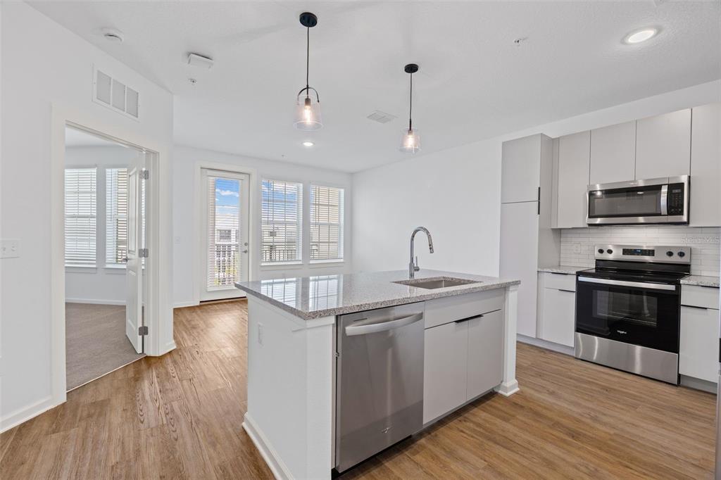 A modern kitchen features light gray cabinets, stainless steel appliances, and a granite-topped island — 1700 RANCH ROAD UNIT A4-7106, NOKOMIS, FL