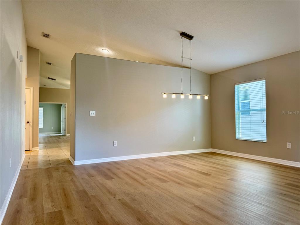 An empty room with light wood-look flooring, a gray accent wall, and a linear pendant light — 10405 SUMMER AZURE DRIVE, RIVERVIEW, FL