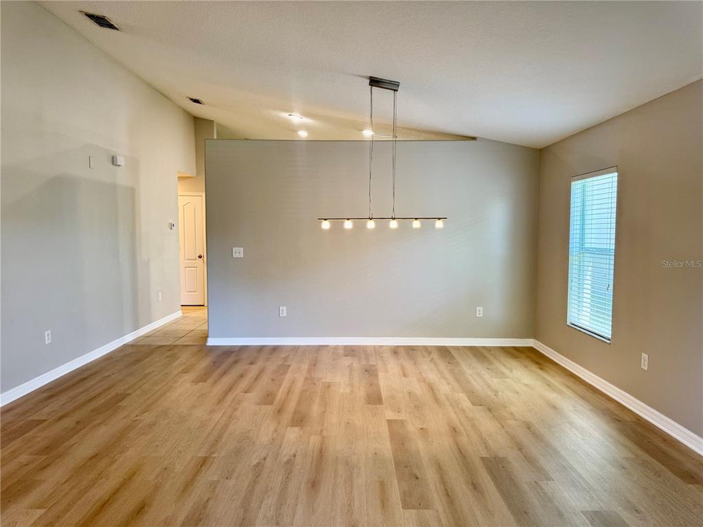 A dining room with light wood-look flooring, a modern linear pendant light, and vaulted ceilings — 10405 SUMMER AZURE DRIVE, RIVERVIEW, FL