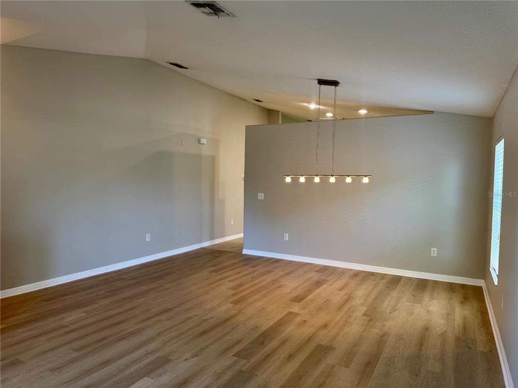 An empty room with light wood-look flooring, gray walls, and a modern linear pendant light — 10405 SUMMER AZURE DRIVE, RIVERVIEW, FL