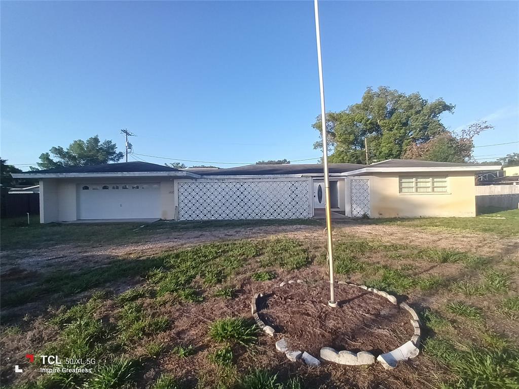 A single-story house with a white garage, decorative lattice screen, and a flagpole in front — 1207 PARKER POINTE LANE, LAKELAND, FL