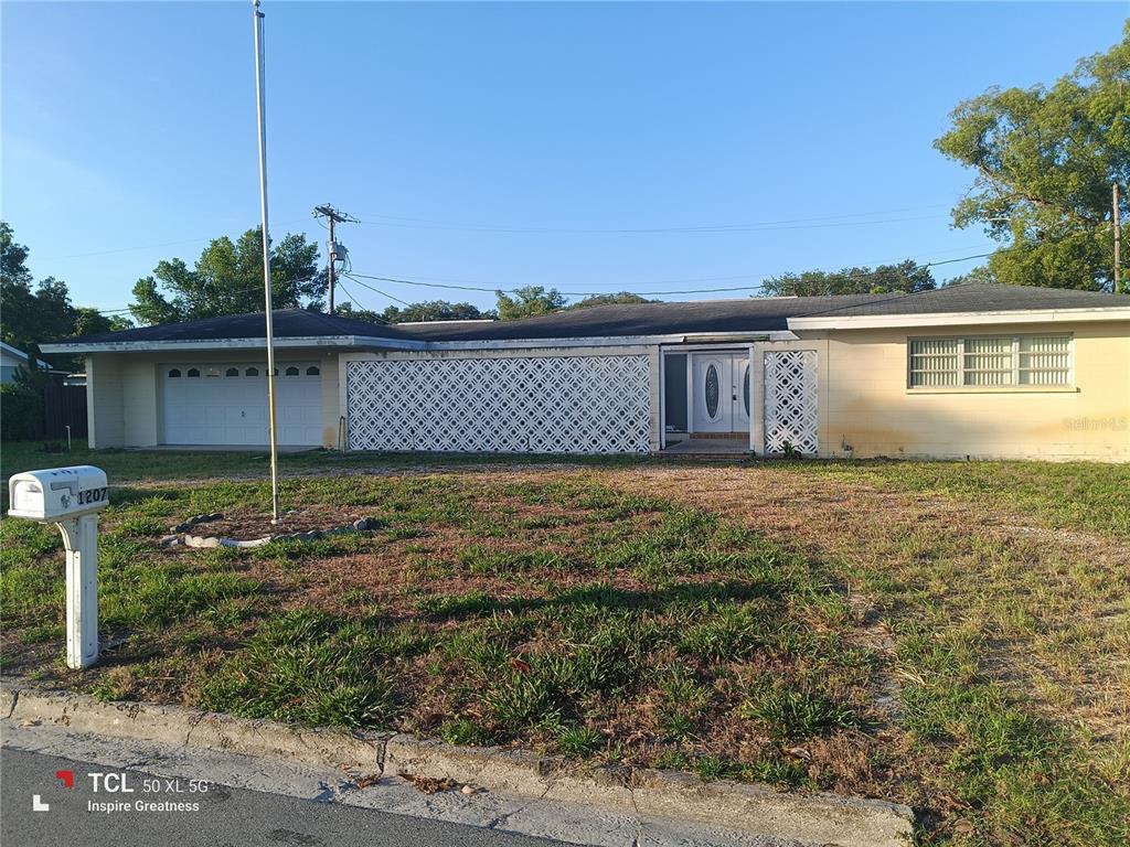 A single-story house with a white garage, decorative lattice screen, and a front lawn — 1207 PARKER POINTE LANE, LAKELAND, FL