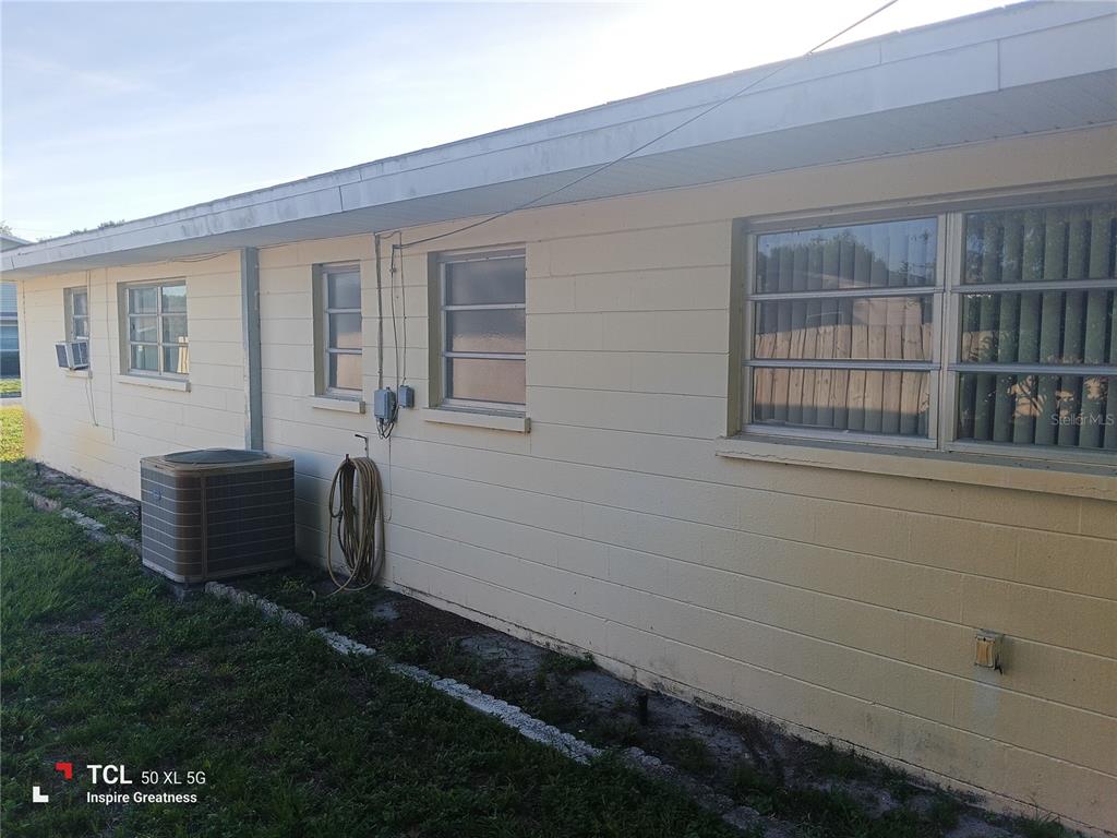 The exterior of a light yellow concrete block house with several windows and an AC unit — 1207 PARKER POINTE LANE, LAKELAND, FL