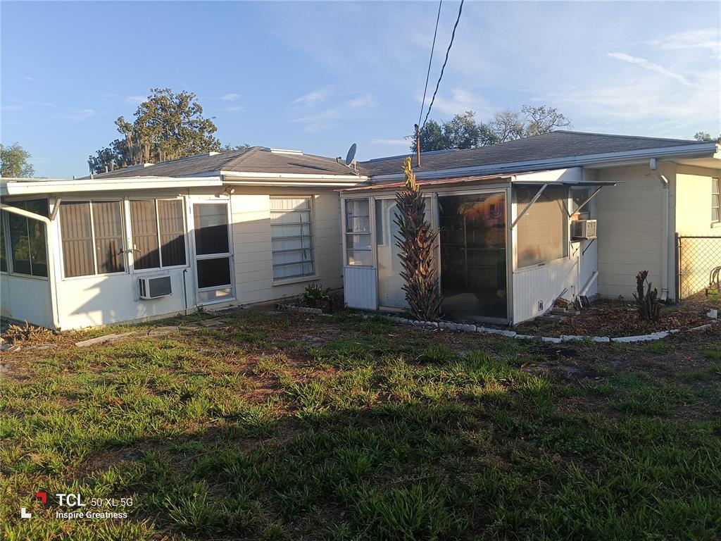 The rear exterior of a single-story house features two enclosed porches and a grassy yard — 1207 PARKER POINTE LANE, LAKELAND, FL