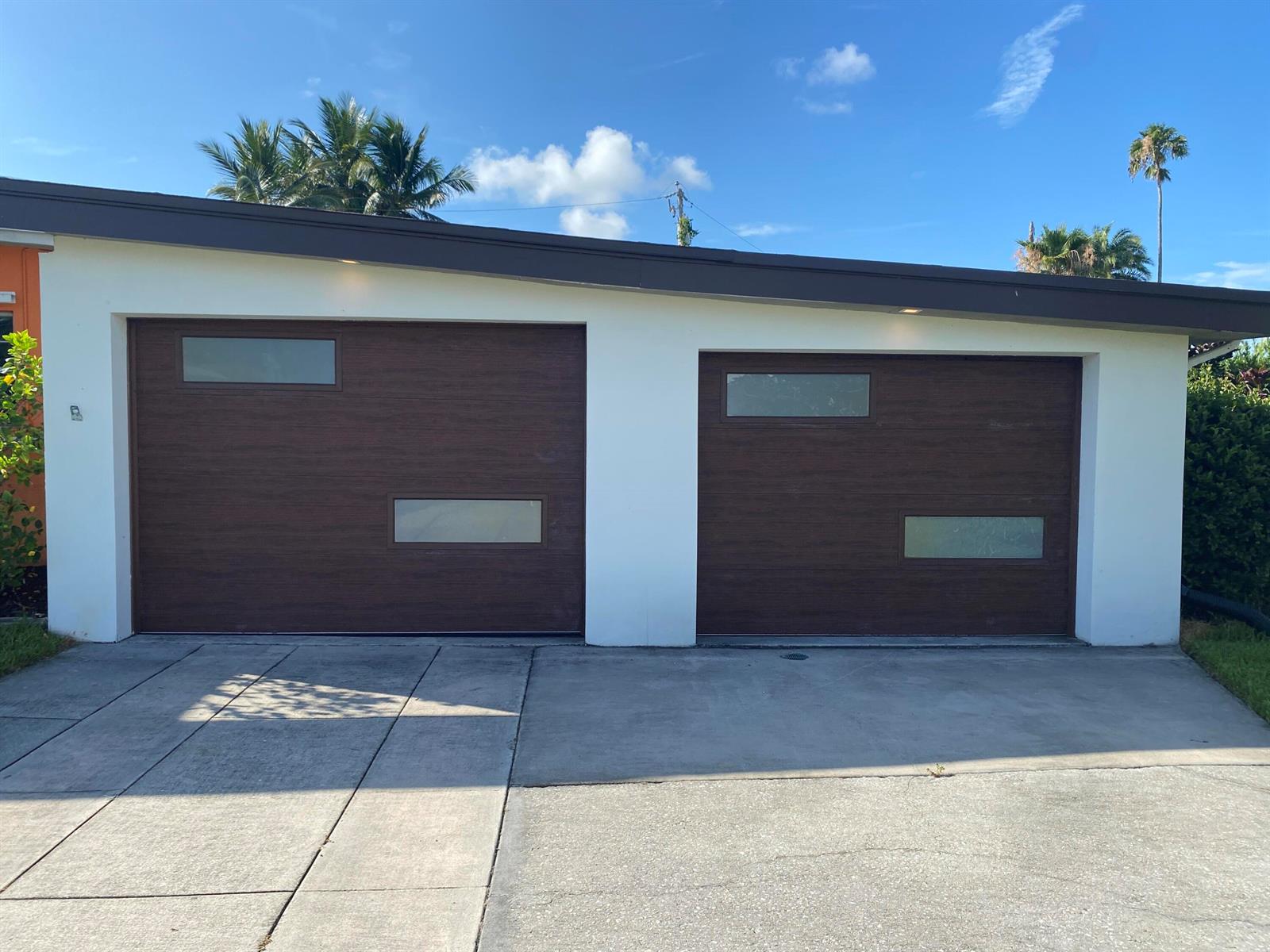 A two-car garage with dark wood-look doors featuring horizontal windows and a white exterior — 403 21st Place SE, Vero Beach FL 32962, VERO BEACH, FL