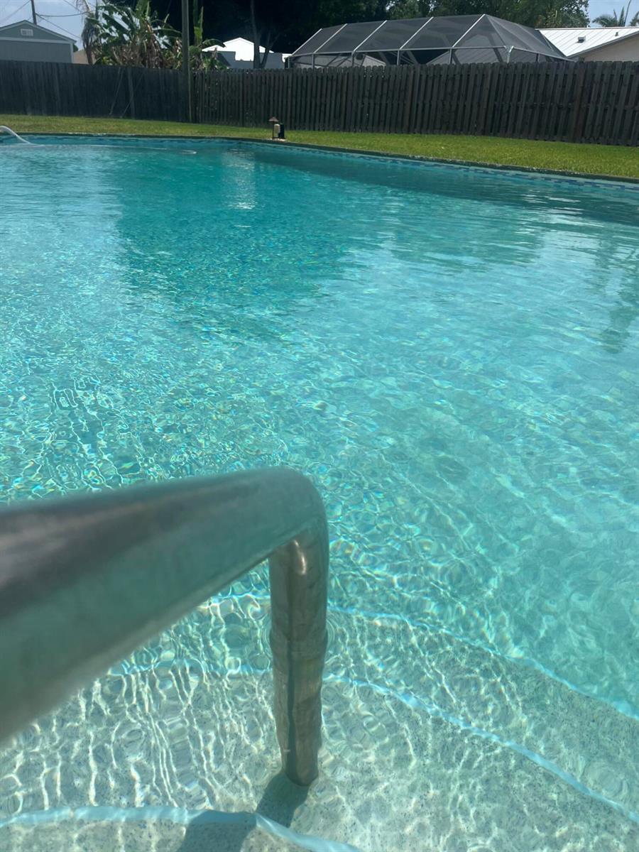 A rectangular swimming pool sits in a backyard next to a house with a patio — 403 21st Place SE, Vero Beach FL 32962, VERO BEACH, FL