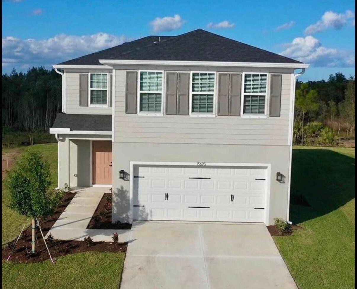 A two-story house with light gray siding, a white garage door, and a pink front door — 15693 SW Twilight Street, FL 34956, FL