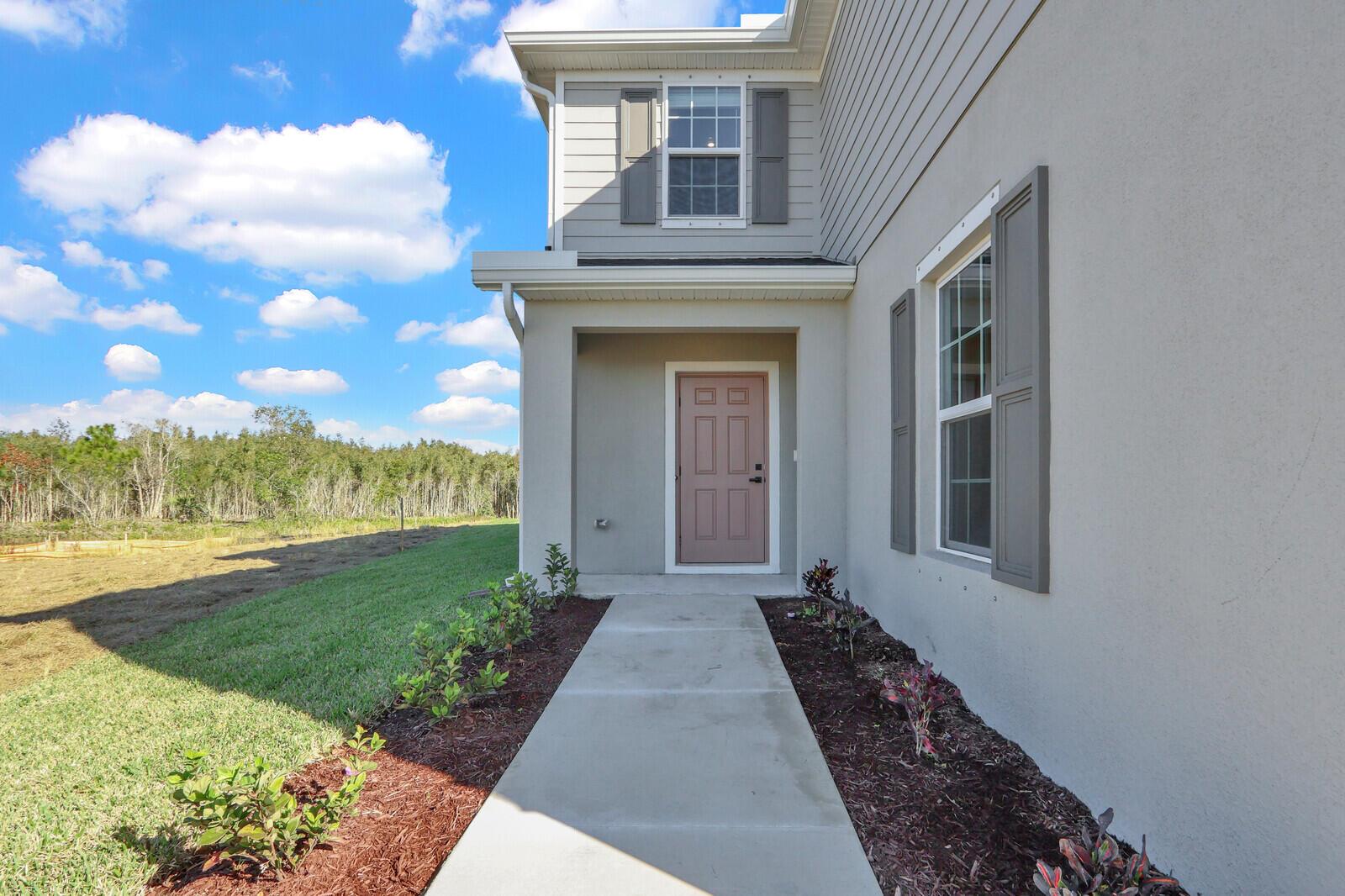 A concrete walkway leads to the front entrance of a two-story house with gray siding — 15693 SW Twilight Street, FL 34956, FL