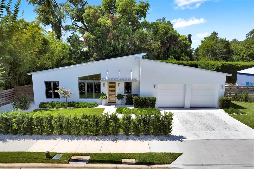 A modern, white, single-story house with a slanted roof, two-car garage, and landscaped front yard — 462 W LYMAN AVENUE, WINTER PARK, FL