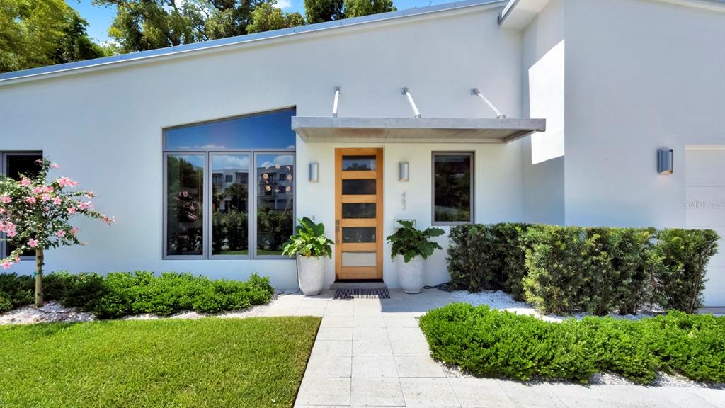 A modern white house features a wooden front door, large windows, and manicured landscaping — 462 W LYMAN AVENUE, WINTER PARK, FL