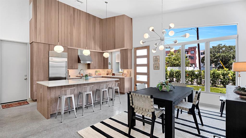 A modern kitchen and dining area feature wood cabinetry, a large island, and floor-to-ceiling windows — 462 W LYMAN AVENUE, WINTER PARK, FL
