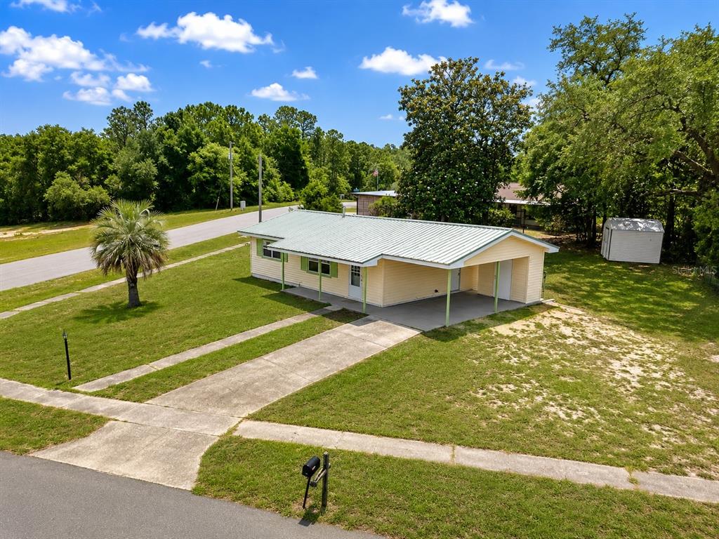An exterior view of a yellow single-story house with a metal roof and carport — 1766 W GARDENIA DRIVE, CITRUS SPRINGS, FL