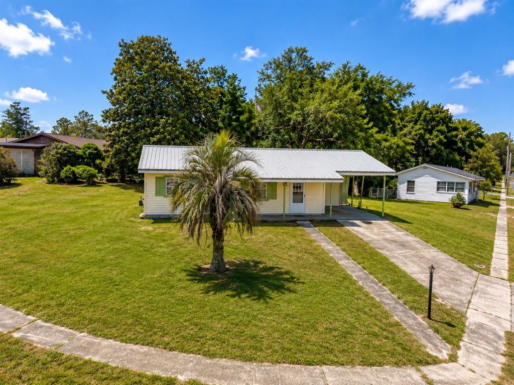 A single-story house with a metal roof, carport, and a palm tree in the yard — 1766 W GARDENIA DRIVE, CITRUS SPRINGS, FL
