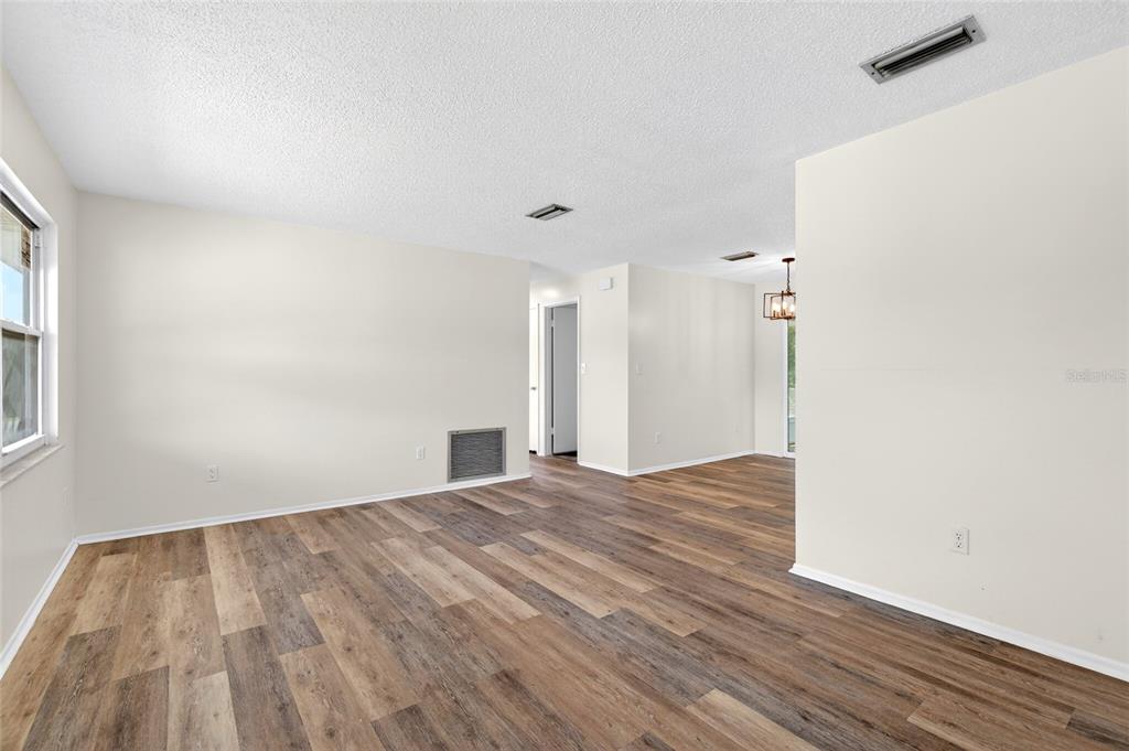 An empty living room features light-colored walls, wood-look flooring, and a ceiling vent — 1766 W GARDENIA DRIVE, CITRUS SPRINGS, FL