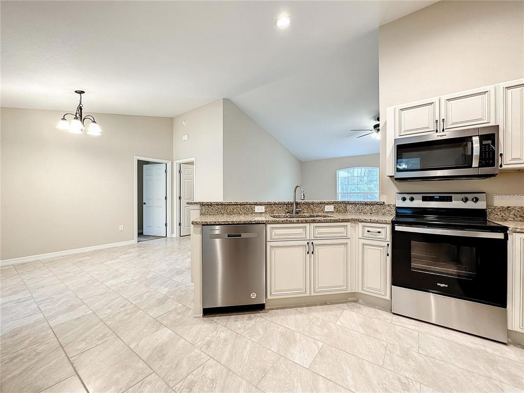 A kitchen with stainless steel appliances, granite countertops, and light-colored cabinets — 4887 SW 159TH LANE ROAD, OCALA, FL