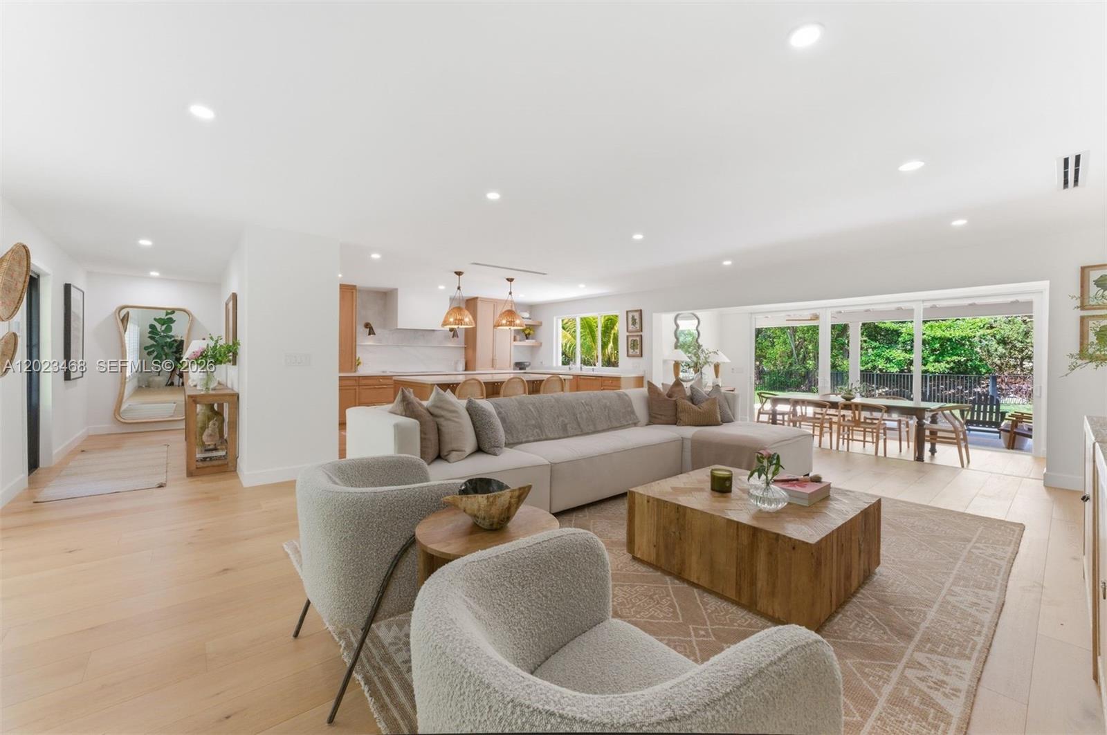 An open-concept living room features a large sectional, two armchairs, and a modern kitchen — 7350 SW 65th Ave, South Miami FL 33143, SOUTH MIAMI, FL