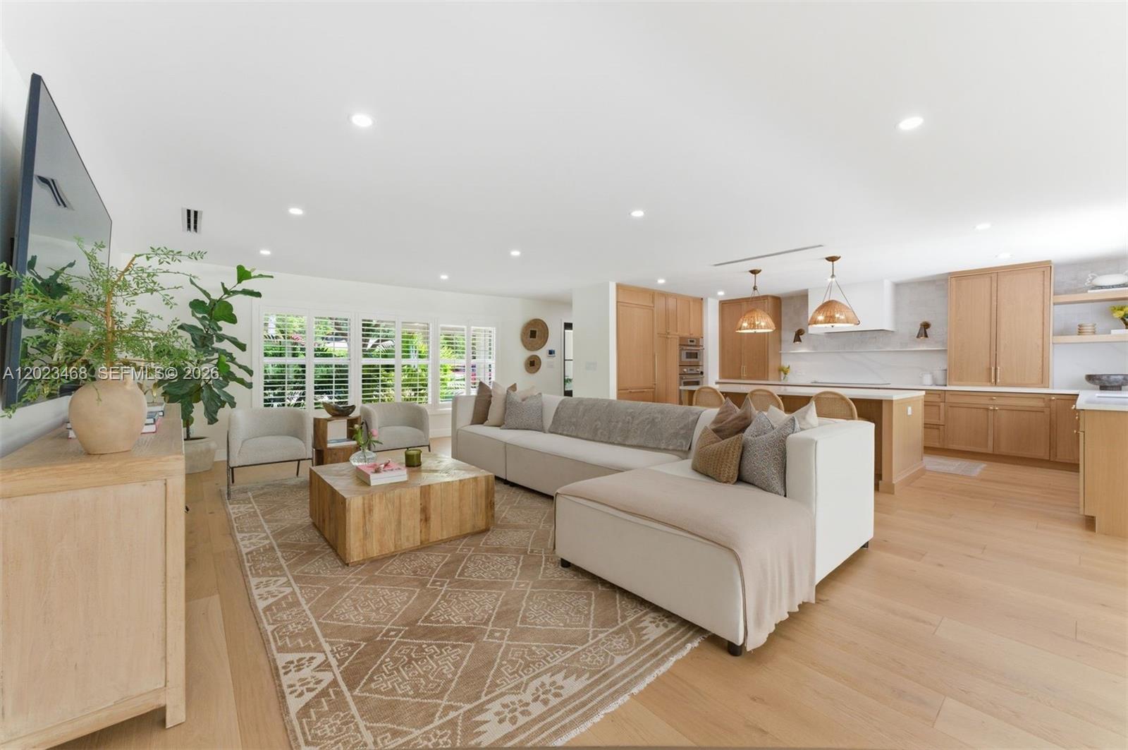 A bright, open-concept living room features light wood flooring, a white sectional, and wooden cabinetry — 7350 SW 65th Ave, South Miami FL 33143, SOUTH MIAMI, FL