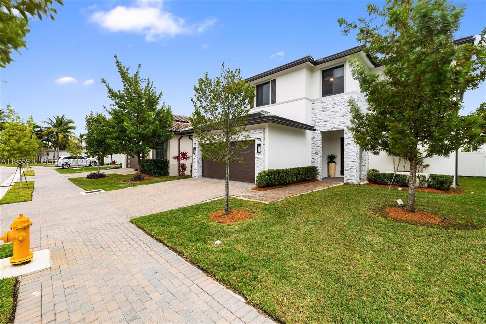 A two-story house with a white facade, stone accents, and a paved driveway — 8086 NW 47th Ter, Doral FL 33166, DORAL, FL