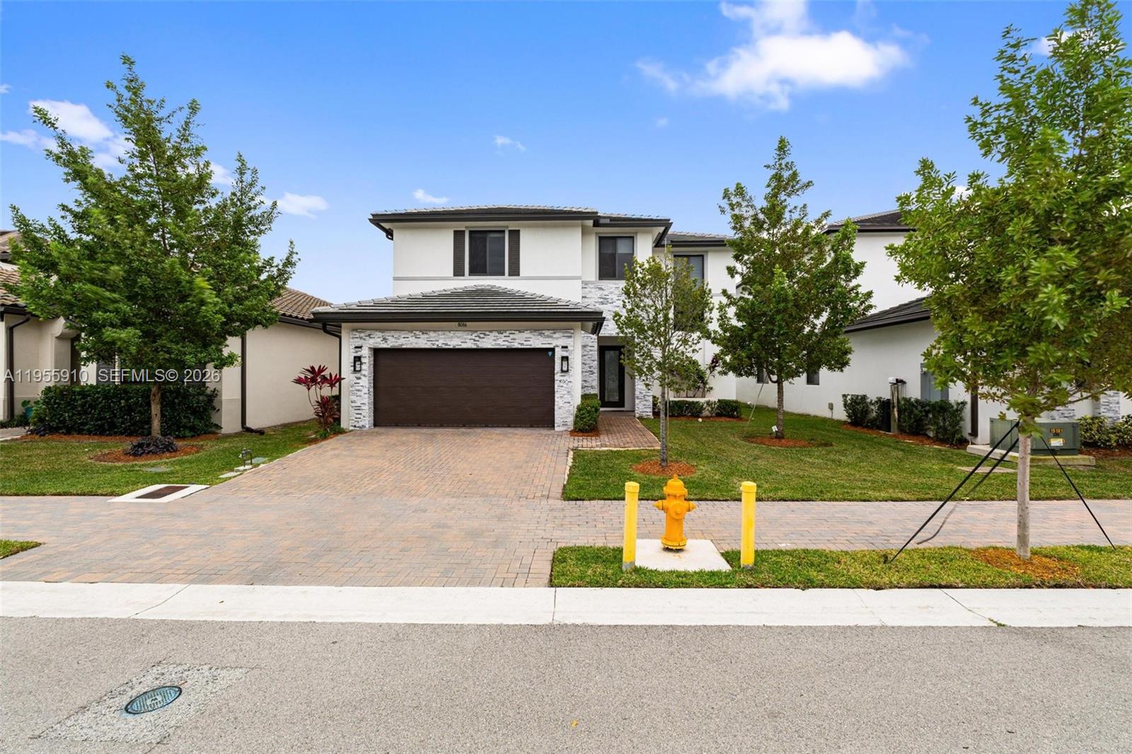 A two-story house with a paved driveway, stone accents, and a yellow fire hydrant — 8086 NW 47th Ter, Doral FL 33166, DORAL, FL