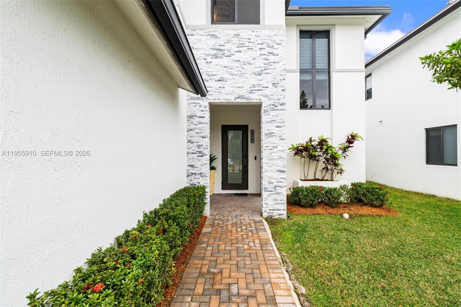 A brick walkway leads to the front entrance of a white house with stone accents — 8086 NW 47th Ter, Doral FL 33166, DORAL, FL