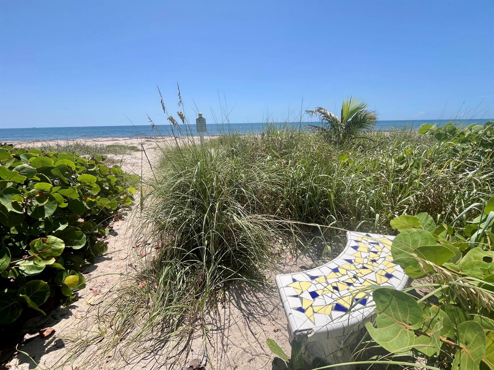 A sandy path leads through beach vegetation toward the ocean, featuring a mosaic-tiled bench — 14 Tropical Drive, Ocean Ridge FL 33435, OCEAN RIDGE, FL