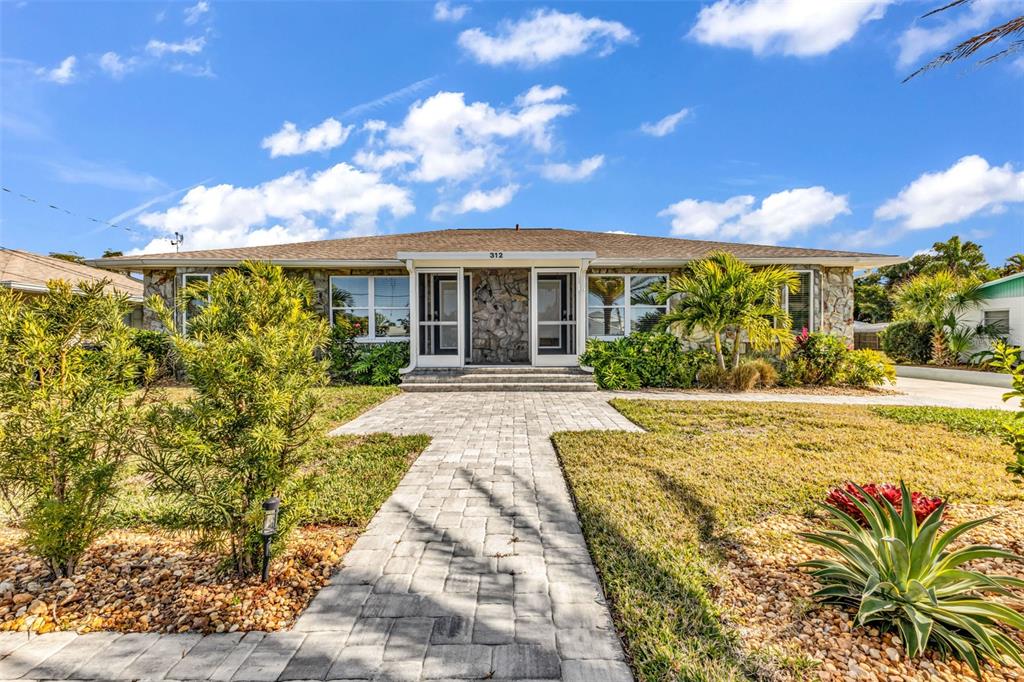 A single-story house with a stone facade, a paved walkway, and a landscaped front yard — 312 BAYSHORE ROAD, NOKOMIS, FL