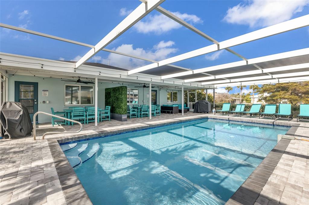 A screened-in patio features a rectangular swimming pool, lounge chairs, and outdoor dining furniture — 312 BAYSHORE ROAD, NOKOMIS, FL
