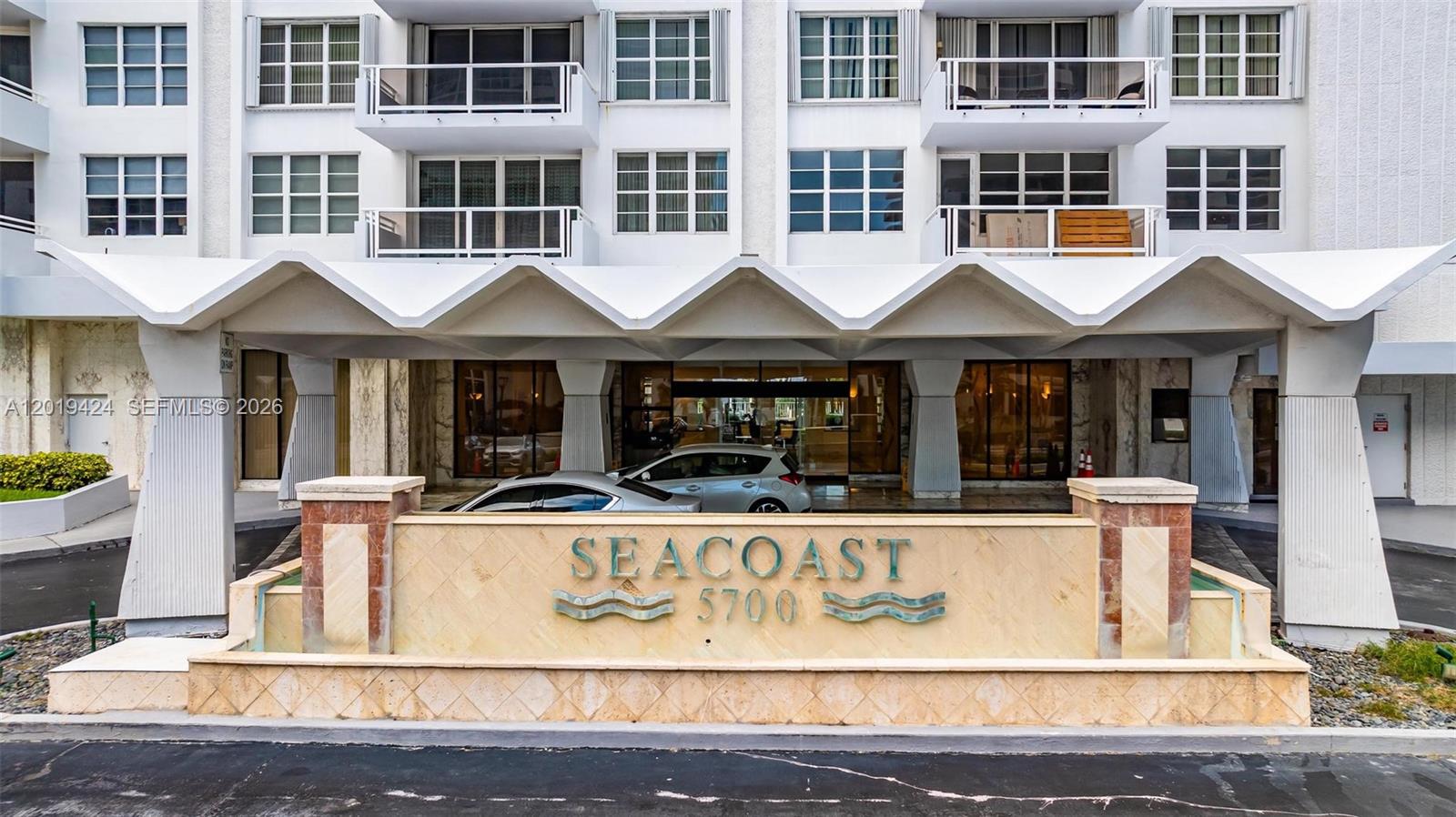 The exterior of a multi-story building features a covered entrance with a stone sign — 5700 Collins Ave # 7J, Miami Beach FL 33140, MIAMI BEACH, FL
