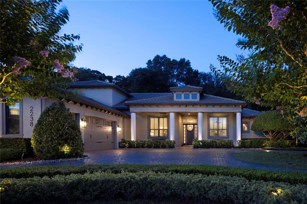 A single-story house with a paved driveway, columns, and a garage at twilight — 2238 SOARING EAGLE PLACE, LAKE MARY, FL
