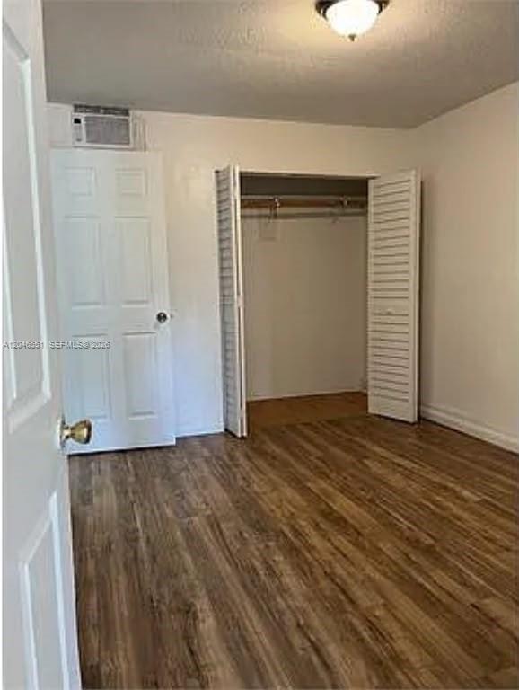 A bedroom with wood-look flooring, a white door, a closet with louvered doors, and an AC unit — 2205 Roosevelt St # 2, Hollywood FL 33020, HOLLYWOOD, FL