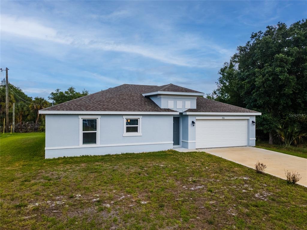 A light blue single-story house with a white garage door and a shingled roof — 4127 CONUS AVENUE, NORTH PORT, FL