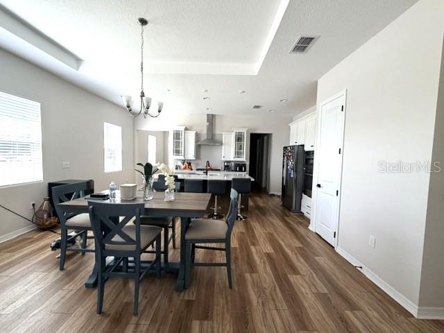 A dining area with a wooden table and chairs sits adjacent to an open kitchen — 1647 KEY BAY TRAIL, KISSIMMEE, FL