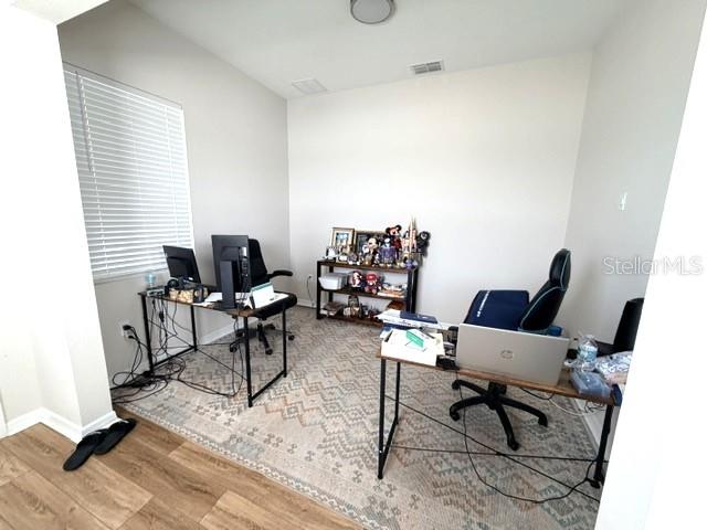 This home office features two desks, a shelving unit, and a patterned area rug — 1647 KEY BAY TRAIL, KISSIMMEE, FL