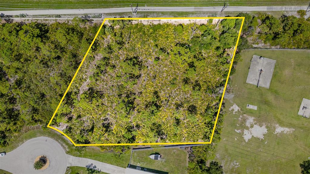 An aerial view shows a vacant, wooded lot outlined in yellow near a residential street — 9437 TREASURE LAKE COURT, ST JAMES CITY, FL