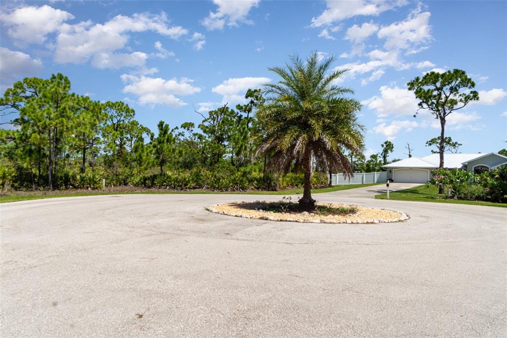 A palm tree sits in the center of a circular driveway in front of a house — 9437 TREASURE LAKE COURT, ST JAMES CITY, FL
